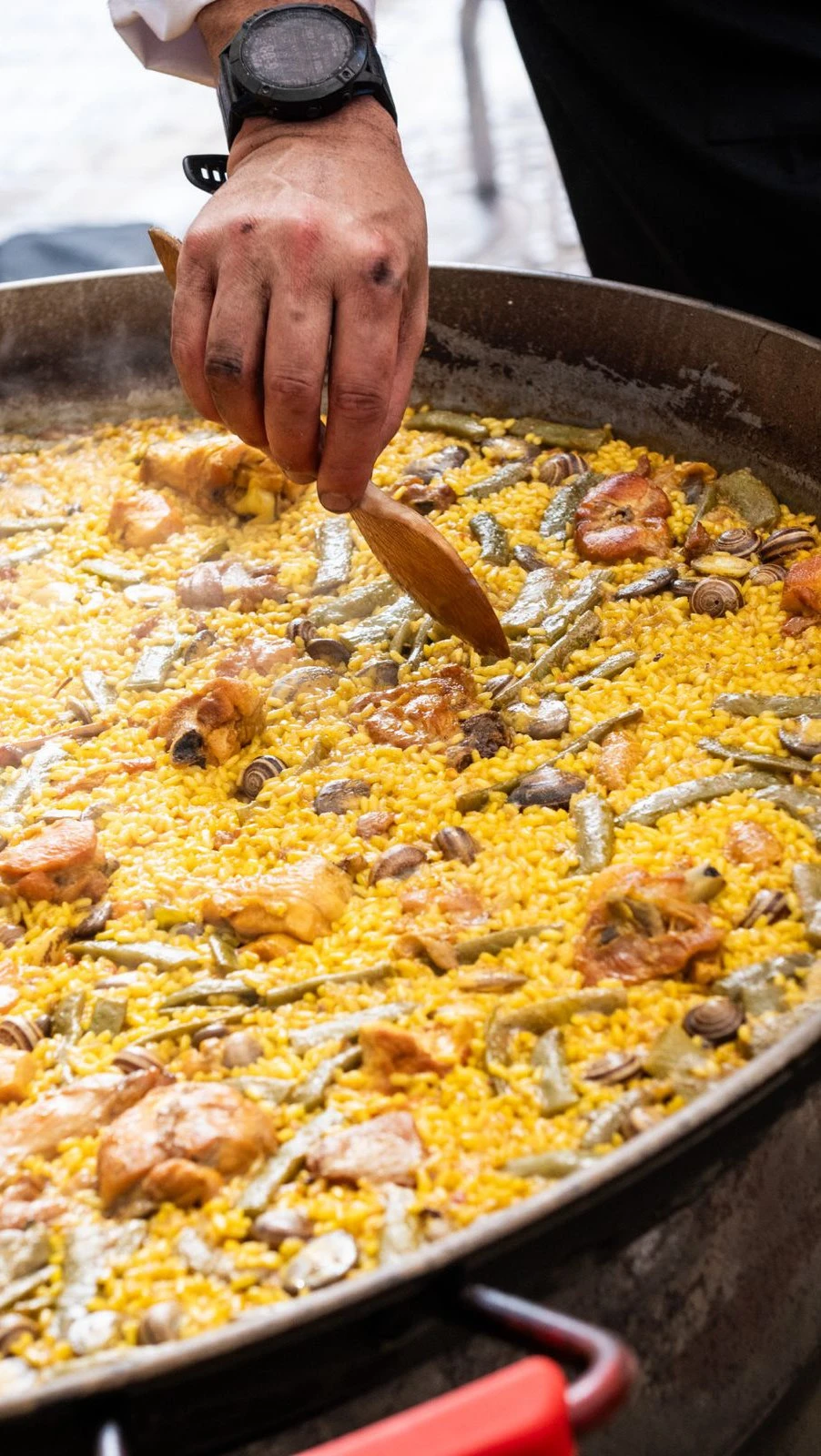 Paella Valenciana tradicional con pollo, conejo y judía verde en una paellera de hierro